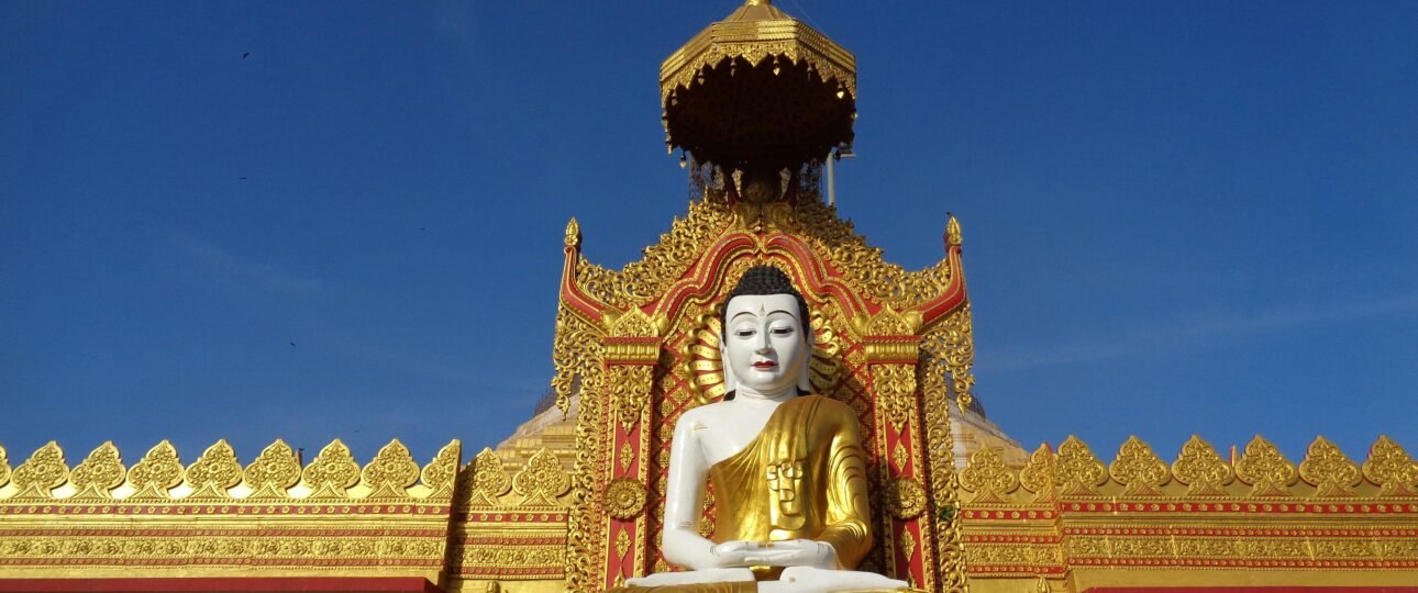 Magnificent golden Buddha statue at a decorated temple entrance in full daylight