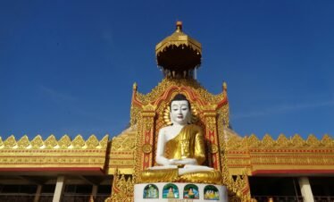 Magnificent golden Buddha statue at a decorated temple entrance in full daylight