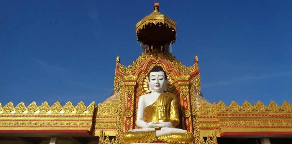 Magnificent golden Buddha statue at a decorated temple entrance in full daylight