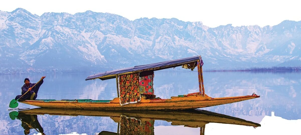 A vibrant shikara on Dal Lake with the stunning Himalayan backdrop, perfect for travel exploration.