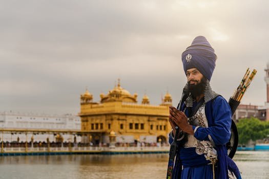 A Sikh warrior in traditional attire stands in reverence at the Golden Temple, Amritsar.